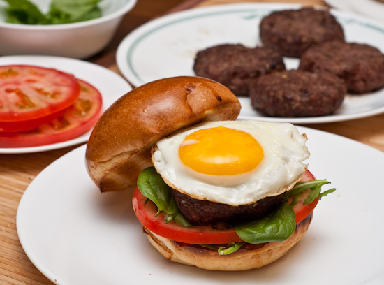 Quarter-pound burger with baby spinach, arugula, tomato, and fried egg on pain au lait bun